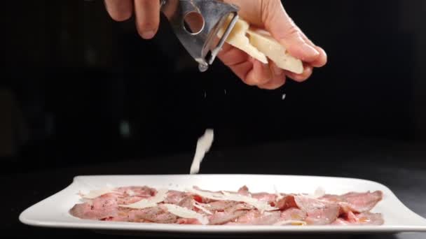 Chef râper le parmesan sur un apéritif de viande froide au ralenti. Ingrédients alimentaires dans la cuisine italienne. Parmesan Tombé dans la charcuterie. Saupoudrer de fromage râpé. Full hd — Video