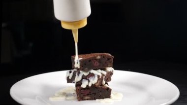 Browni tatlısına buzlu şeker dökmek. Ağır çekim. Kahve evinde tatlı yapmak. Bir yığın browni beyaz tabakla süsleniyor. Tam Hd