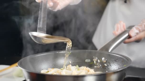 Restaurante de frutos do mar italiano. Close-up tiro de chef derramando caldo de peixe de concha em risoto. Movimento lento. Cozinha italiana tradicional. hd completo — Vídeo de Stock