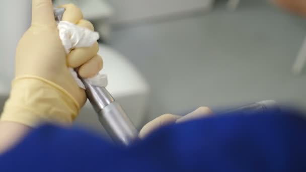 Assistente feminina da clínica odontológica limpeza e desinfecção de ferramentas e instalações dentárias. Tiro de perto das mãos segurando brocas e soprando a sujeira do lugar de difícil acesso. 4 k vídeo — Vídeo de Stock