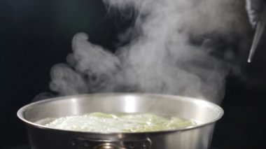 İtalyan mutfağı. Makarna kaynar suda pişiyor. Beyaz duman ağır çekimde siyah arka planda sıcak tencerenin üzerinde yükseliyor. Restoranda yemek pişirmek. Lezzetli İtalyan makarnası. Tam Hd