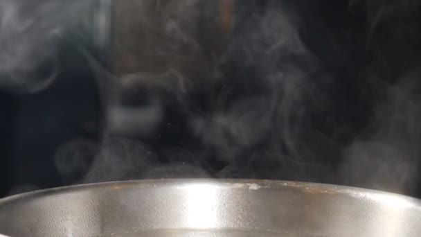 Fumaça branca em câmera lenta subindo acima da frigideira quente no fundo preto. Cozinhar no restaurante. Prato delicioso sendo cozido na cozinha. Nuvens de vapor ou vapor. hd completo — Vídeo de Stock