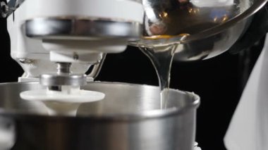 Şef elektrikli karıştırıcı kasesine yumurta ekliyor. Makarna ve pastaya hamur hazırlamak için malzemeler karışımdır. Pasta yapmak için lezzetli krema hazırlıyorum. Ağır çekim. Ev yapımı yemek. Tam Hd