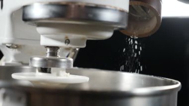 Şef hamuru pişirmek için hazırlar. Elektrikli karıştırıcı kasesine tuz ekliyorum. Ağır çekim. Şef tuz kristalleri serpiyor. Tam Hd
