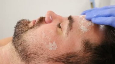 Güzellik kliniği. Yüz gerdirme ve Yaşlanma Karşıtı Kozmetoloji. Kadın kozmetik uzmanı tarafından yapılan temizlik operasyonunda sakallı yakışıklı bir adam. Adam cilt bakımını tazeliyor. 4 bin.