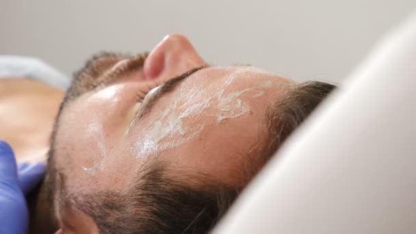 Blahobyt, koncept zdravotní péče. muž ležící na gauči na kosmetické klinice na ošetření obličeje. Hezký mužský klient při čištění obličeje. Kožní péče o pleť dermatologické léčby. 4 k video — Stock video
