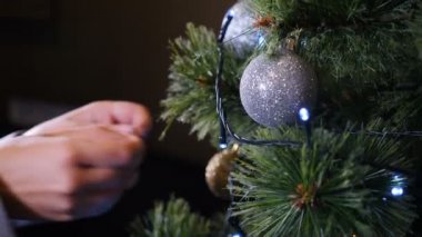 Noel zamanı ve mutlu yeni yıl sembolleri. Noel ağacını balo ve oyuncaklarla süsleyen kadın, yakın plan, kış tatili festival sezonu hazırlığı, yeni yıl kutlaması. 4k video