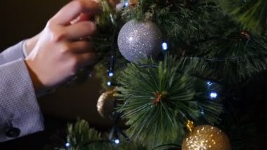 Noel zamanı ve mutlu yeni yıl sembolleri. Noel ağacını balo ve oyuncaklarla süsleyen kadın, yakın plan, kış tatili festival sezonu hazırlığı, yeni yıl kutlaması. 4k video