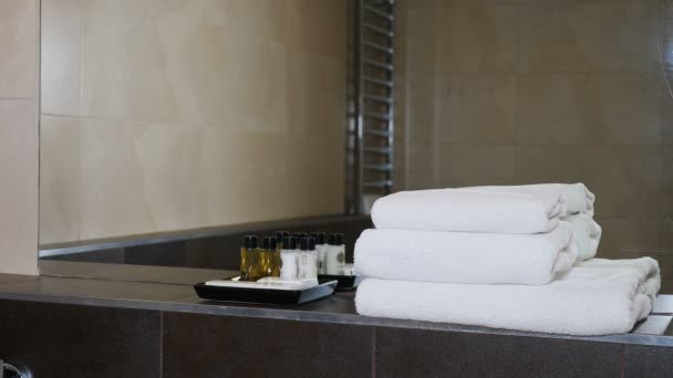 Uvnitř hotelových apartmánů. Vybavení koupelny: sprchový gel, šampon, kondicionér a stack bílých ručníků. Moderní koupelna zrcadlo hotelového resortu. Zdraví, hygiena a čistota. 4 k — Stock video