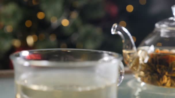 Gyönyörű ünnepi újév és karácsonyi hangulat. A gőz lassan emelkedik fel a csészéből forró teával. Gőzölgő csésze forró ital karácsonyfával a háttérben. Teljes hd — Stock videók
