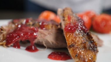 Güzel mutfak. Restoranda yemek pişirmek. Kızarmış ördeğin üzerine lezzetli sos dökülüyor, ağır çekim. Pişmiş kümes hayvanlarının üzerine sıvı sos dökülüyor. El ele tutuşan soslu sandviç tabağı. Tam Hd