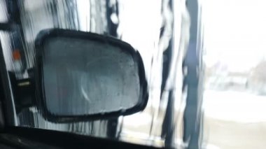 Otomatik yıkama makinesinde yıkanan içerideki arabanın görüntüsü. Araba yıkama servisi iş başında. Sıcak hava akışıyla kurumak. Yıkanmanın son kısmı. 4k video