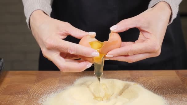 Kvinnliga händer bryter ägg till pulver. Sakta i backarna. Knäcka råa ägg medan du gör deg för pasta eller bakverk i hemköket. Livsmedelsvideo. Baker knådar deg till tårta. Fullständig hd — Stockvideo