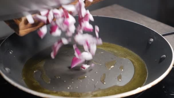 Smażenie posiekanej cebuli na patelni. Zwolnij trochę. Szef kuchni wlewa kawałki cebuli do garnka skwierczącego w oleju. Gotowanie sosu makaronowego. Pełny hd — Wideo stockowe