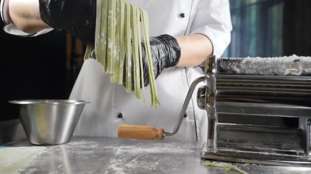 健康的なイタリア料理。パスタマシンでパスタを作る。スローモーション。レストラン料理。圧延機で自家製麺を作る。シェフの手の上に新鮮なスパゲティ — ストック動画