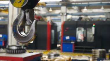 Fabrika vinci kancası ve endüstriyel arka plan. Endüstriyel fabrikada asılı metal vinç kancası. Arkaplanda bulanık ekipman ve hazırlanmış yataklar olan bitki iç mimarisi. 4k video