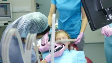 Modern diş kliniği. Gaz-oksijen anestezisi ile uzun süreli bir işlem. Küçük kız diş bakımı yaptırıyor. Bir grup diş hekimi aşırı aktif çocuk için solunum ilacı kullanıyor. 4k video