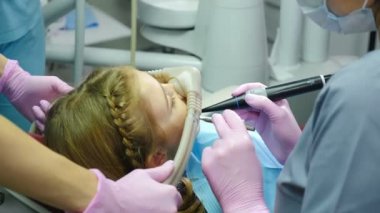 Dişçi ve diş hekimlerinden korkan bir kız. Solucan Yatıştırıcı kullanan doktorlar. Modern prosedürleri olan bir dişçi kliniği. Eller azot oksit anestezi cihazından yüz maskesi tutuyor. 4 bin.