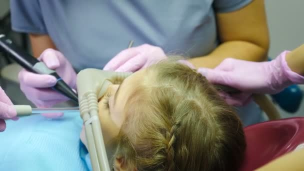 La dentisterie moderne. Petite fille obtenant une sédation par inhalation pendant le traitement des dents dans une clinique dentaire. Médecin portant un masque à gaz Laghing pour se détendre et calmer jeune patient hyperactif vers le bas. 4 k — Video