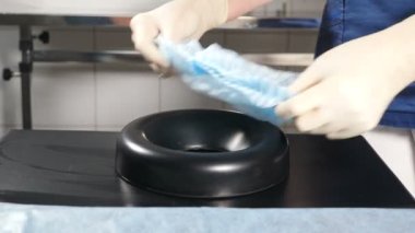Diş tedavisinden önce cerrahi kanepenin başlığını çıkarılabilir başlığa tıbbi şapka takmak. İşlem, sterilizasyon ve diş temizleme ünitesi. Cerrahi aktivite için hazırlık. 4k video