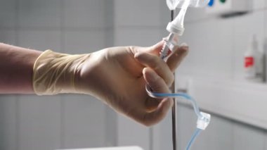 Hastane ve tıbbi bakım konsepti. Hastanede serum hazırlayan hemşire damar içi infüzyon için damar içi serumu ayarlıyor. Hastaya terapi. 4k video