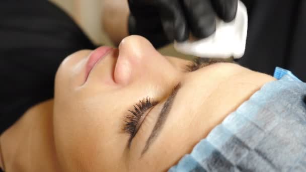 Esteticista profesional lava los ojos femeninos y la cara antes del procedimiento de maquillaje permanente. Clínica de belleza Mujer joven recibiendo tratamiento facial. 4 k vídeo — Vídeos de Stock