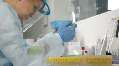 Tıbbi üniformalı kadın bilim adamının araştırma laboratuarındaki arka görüntüsü. Yakın plan. İnsan analizi konsepti. Maskeli laboratuvar asistanı. Laboratuvar çalışanı. Laboratuvarda çalışan bir kadın. 4k görüntü