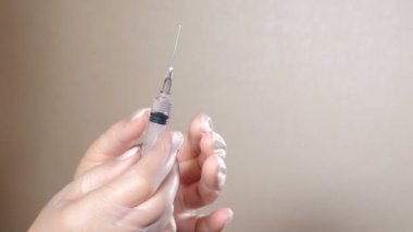 Kadın, şırıngayı aşıyla tutan elleri ve parmakları kıvrılmış. Tek kullanımlık koruyucu eldiven verin. Doktor aşı için şırınga hazırlıyor, COVID 19 koronavirüs. 4k video