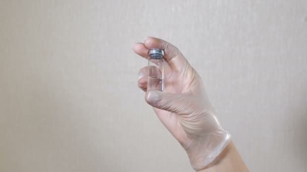 Médecin ou infirmière tenant une ampoule avec un vaccin contre le coronavirus, la grippe ou une autre infection à la main. bouteille en verre avec liquide de vaccin transparent. Soins de santé et concepts médicaux. Vidéo 4 k — Video