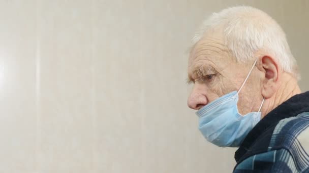 Температура тела. Пожилой человек в маске для лица в больнице. медицинский осмотр перед вакцинацией против ковида-19. использование бесконтактного инфракрасного цифрового термометра. Врач измеряет температуру больного — стоковое видео