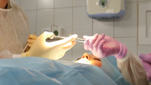 Assistent geeft medisch tandheelkundig hulpmiddel aan chirurg tijdens het uitvoeren van chirurgische ingreep. Tandheelkundige kliniek. Verpleegkundige geven en tandarts nemen spuit om vrouwelijke patiënt te verdoven. Moderne tandartspraktijk. 4 km — Stockvideo
