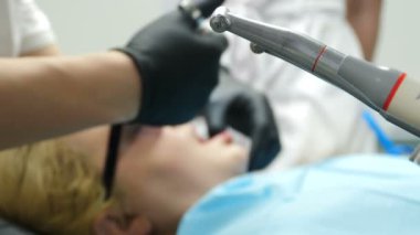Dişçiye git. Kadın bir hasta. Diş hekimi muayene ediyor ve dişleriyle çalışıyor. Yakın plan. Yan görüş. Orta yaşlı bir kadın diş tedavisi görüyor. 4 k video