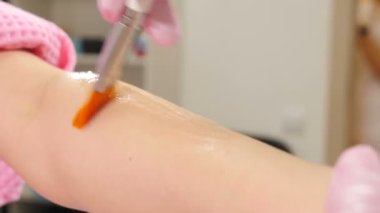 Güzellik uzmanı ellerine ve kollarına lazer tüy dökücü jel sürüyor. Kadın müşteri modern güzellik salonunda lazer tüy çıkarma prosedürü uyguluyor, spa prosedürü. Lazer saç kesimi, fotoepilasyon, vücut ve deri.