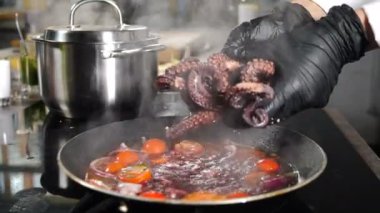 Şef tavaya ahtapot dokunaçlarını kaynar et suyuyla dolduruyor. Lokanta mutfağında sulu ahtapot dokunaçları. Ahtapot usulü Fransız usulü yemek pişirme, restoran yemeği. 4 k video