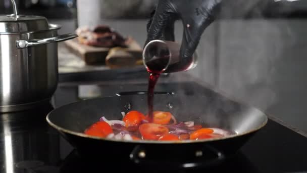 Chef koken gastronomische schotel, giet rode wijn in koekenpan. Heerlijke saus bereiding. Gestoofde groenten met rode wijn. Gezond eten en vegetarisch concept. Kok koken in restaurant. 4 k video — Stockvideo