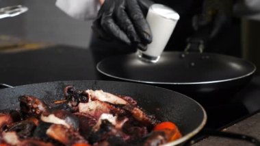Lüks restoran. Ahtapot arıyor. Kızartma tavasına süt dök. Ahtapot pişir. Geleneksel Akdeniz mutfağı. Deniz ürünleri. Restoran mutfağında siyah eldivenli bir şef. 4 k video