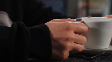 Kafede ya da restoranda ömür boyu. Yan görüş. Masada beyaz kahve fincanı tutan bir kadın. Restoran sokak yemekleri yaşam tarzı. Kahve dükkanı, iş yemeği, yağmurlu hava, sıcak zaman. Tam Hd