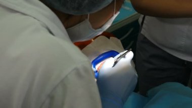 Modern diş kliniğinde profesyonel diş beyazlatma ya da beyazlatma prosedürü hazırlığı. Jöleli sakız izolasyonu. LED beyazlarken koruyucu gözlüklü hasta. 4 k video