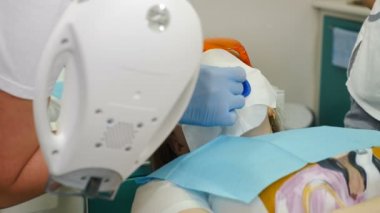 Modern diş kliniğinde profesyonel diş beyazlatma ya da beyazlatma prosedürü hazırlığı. Çiklet izolasyonu ve LED beyazlatma için diş kaplaması. Sandalyedeki koruyucu gözlüklü hasta. 4 bin.