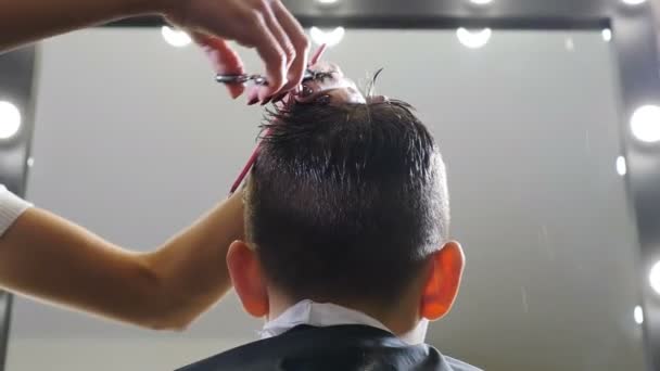 Salão de cabeleireiro. Corte de cabelo de crianças em salão. Cabeleireiro. cabeleireiro corta cabelo com tesoura. Estilo de cabelo infantil. cabeleireiro fazendo penteado elegante. Corte de cabelo profissional para — Vídeo de Stock