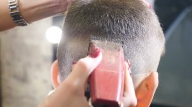 Kuaför salonu. Kuaförde çocuk tıraşı. Küçük çocuk kuaförlüğü. Çocuk saçı şekillendirme. Saç stilisti, saç kesimi ve saç kesimiyle şık saç kesimi yapıyor. Berber dükkanındaki çocuklar için profesyonel saç kesimi