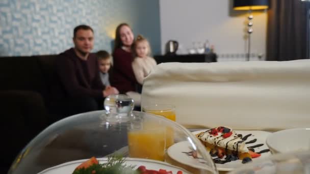 Délicieux petit déjeuner en chambre d'hôtel. Livrer et servir de la nourriture pour la famille le matin. plats couverts de cloche de verre. Petit déjeuner pour quatre personnes à l'hôtel de luxe. Assiettes pleines de nourriture, jus sur la table, 4 k — Video