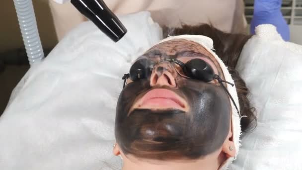 Cosmetologist making carbon face peeling procedure. Laser pulses clean skin of face. Hardware cosmetology treatment. Process of photothermolysis, warming skin, laser peeling. Facial skin rejuvenation — Stock Video