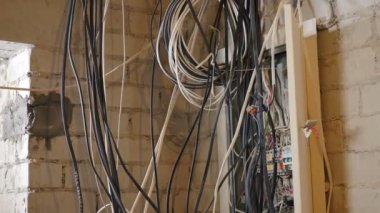 Ev geliştirme konsepti. Elektrikçi dairedeki kablolarla meşgul. İnşaatçı elektrik üretiyor. Elektrik güç sistemi kabloları. İşteki adam yeni binaya kablo döküyor. 4 k video