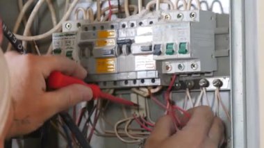 Elektrik tesisatçısı, apartman dairesinin duvarındaki bağlantı kutusunda elektrik kablolarıyla meşgul. Bükülmüş yüksek gerilim kabloları yalıtımı, yeni dairedeki açık kabloların profesyonelce yenilenmesi. 4