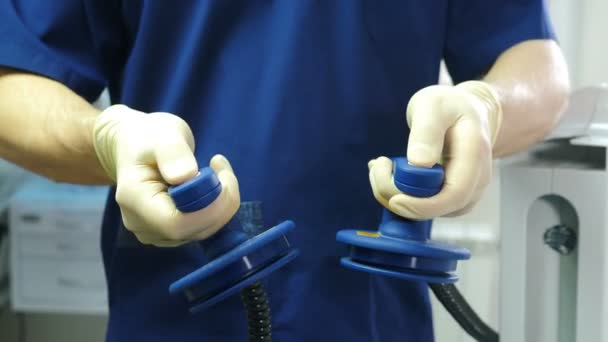 Reanimador sosteniendo electrodo de desfibrilación en la mano. Preparándose para la desfibrilación para salvar vidas. Equipamiento en clínica moderna. Doctor preparándose para dar reanimación al paciente en la sala de emergencias. 4. — Vídeo de stock