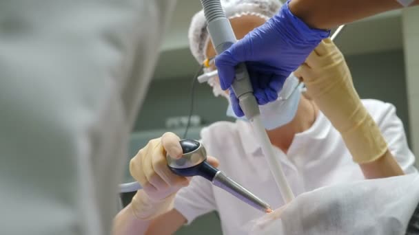 Higienista profesional en el trabajo en odontología moderna. Dentista con microscopio binocular haciendo limpieza de dientes. blanqueamiento dental y limpieza por ultrasonido. Higiene profiláctica oral. 4 k vídeo — Vídeo de stock