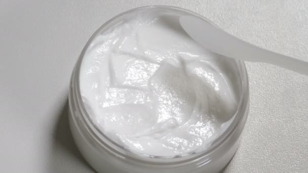 L'esthéticienne prend de la crème à la spatule. Vue de dessus. Procédure de beauté dans le salon moderne. traitement des soins de la peau en clinique de cosmétologie. Nettoyage ou hydratation de la peau. Crème naturelle de pot. Vidéo 4 k — Video