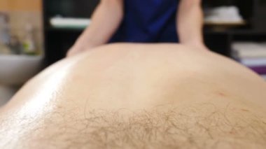 Sağlık hizmeti prosedürü. Erkek sırt masajı yapan bir masör. Doktor terapist masaj masasında yatan erkek hastaya elle masaj yapıyor. Profesyonel masaj. 4 k video