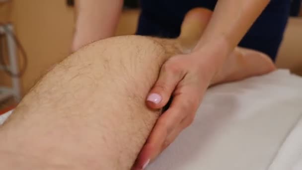 Procedura opieki zdrowotnej. masażysta robi sportowy masaż męskiej nogi. Lekarz terapeuta wykonujący ręczny masaż pacjentom leżącym na stole do masażu. Profesjonalny masaż. 4 tys. wideo — Wideo stockowe